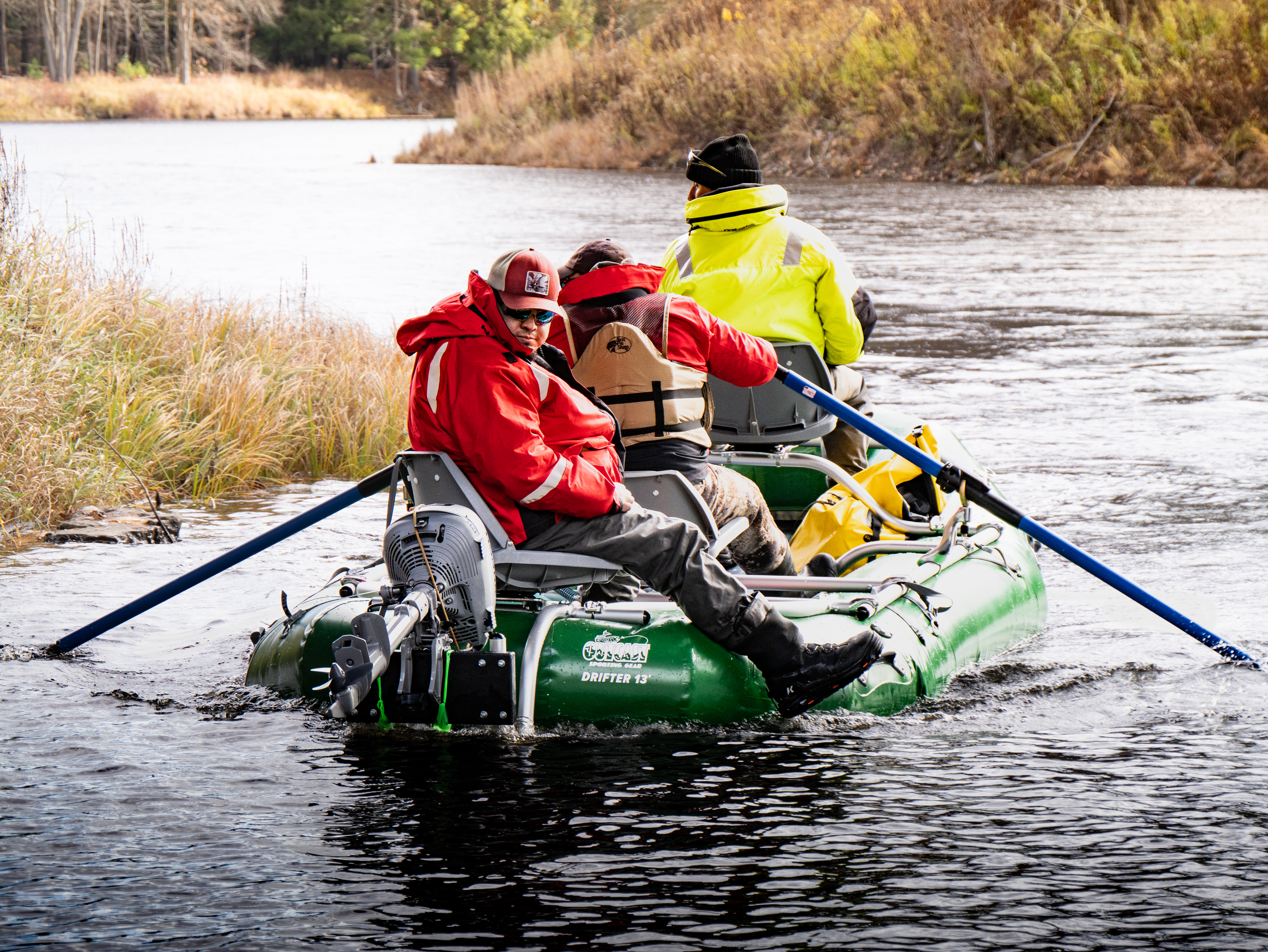 Researchers rowing a green inflatable raft equipped with an outboard motor down the river.